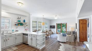 A spacious kitchen with white cabinetry, a central island, and a dining area with chairs.