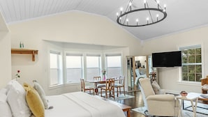 A spacious bedroom with a large bed, a dining area, and a TV. - Jubilee Suites Boutique B&B (Fairhope)