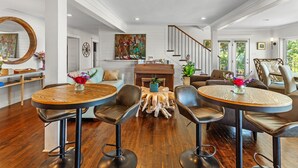 A spacious living room with a wooden coffee table, leather chairs, a fireplace, and a staircase. - Jubilee Suites Boutique B&B (Fairhope)