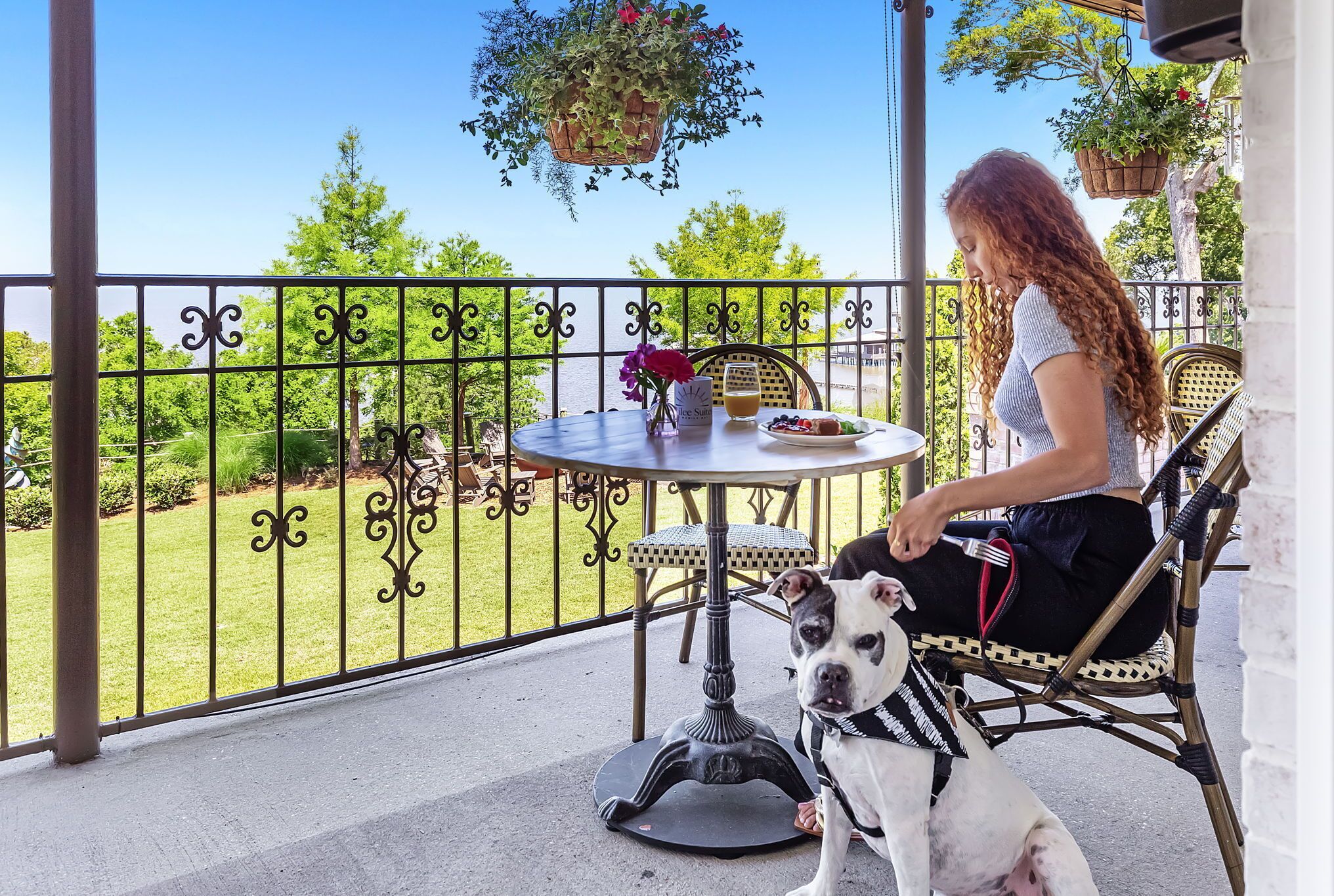 Un balcon avec une table, des chaises et des jardinières suspendues.