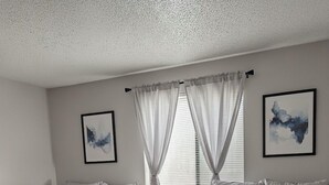 Habitación doble con dos camas, una ventana con cortinas y dos cuadros enmarcados en las paredes.