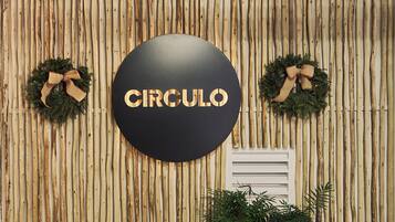 A wall with vertical wooden slats, a circular sign with the word "CIRCULO" in the center, and two wreaths on either side.