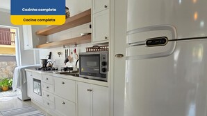 A modern kitchen with white cabinets, a built-in oven, a microwave, and a refrigerator. - Stay in a good location in the city center of Bombinhas. (Bombinhas)