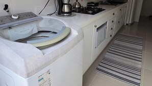 A modern kitchen with a built-in washing machine, a coffee maker, and a gas stove. - Stay in a good location in the city center of Bombinhas. (Bombinhas)