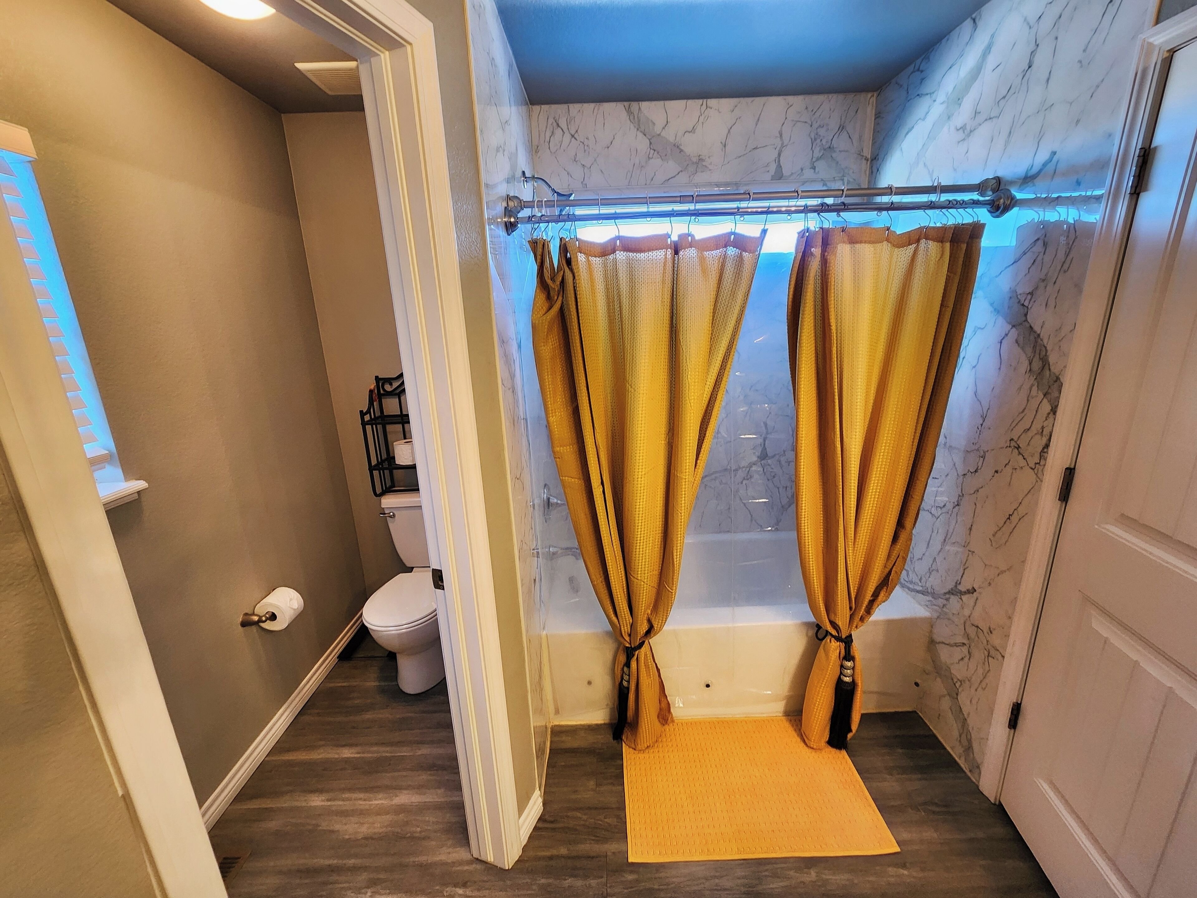 Une salle de bain avec un mur en marbre, une baignoire et un rideau de douche.