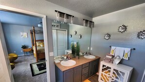 A bathroom with two sinks, a mirror, and a vanity with decorative items. - Modern Family Getaway with Mountain Views (Colorado Springs)