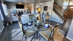 A dining area with a glass table, chairs, and a Christmas tree. - Modern Family Getaway with Mountain Views (Colorado Springs)