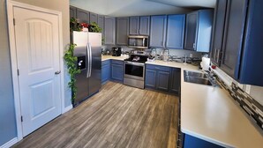 A modern kitchen with grey cabinets, stainless steel appliances, and a wooden floor. - Modern Family Getaway with Mountain Views (Colorado Springs)
