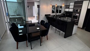 A modern kitchen with a central island, black chairs, and a dining table.