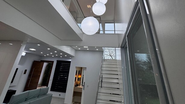A modern interior with a staircase, a sofa, and pendant lights.