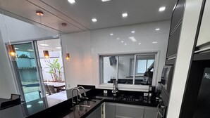 A modern kitchen with black countertops, stainless steel appliances, and a large window.