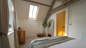 A bedroom with a bed, a wooden dresser, a mirror, a window, and a radiator. - Cosy retreat in Devon, The Old Chapel (Feniton)