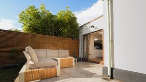 An outdoor seating area with a sofa and ottoman, a wooden fence, and a building entrance. - Cosy retreat in Devon, The Old Chapel (Feniton)