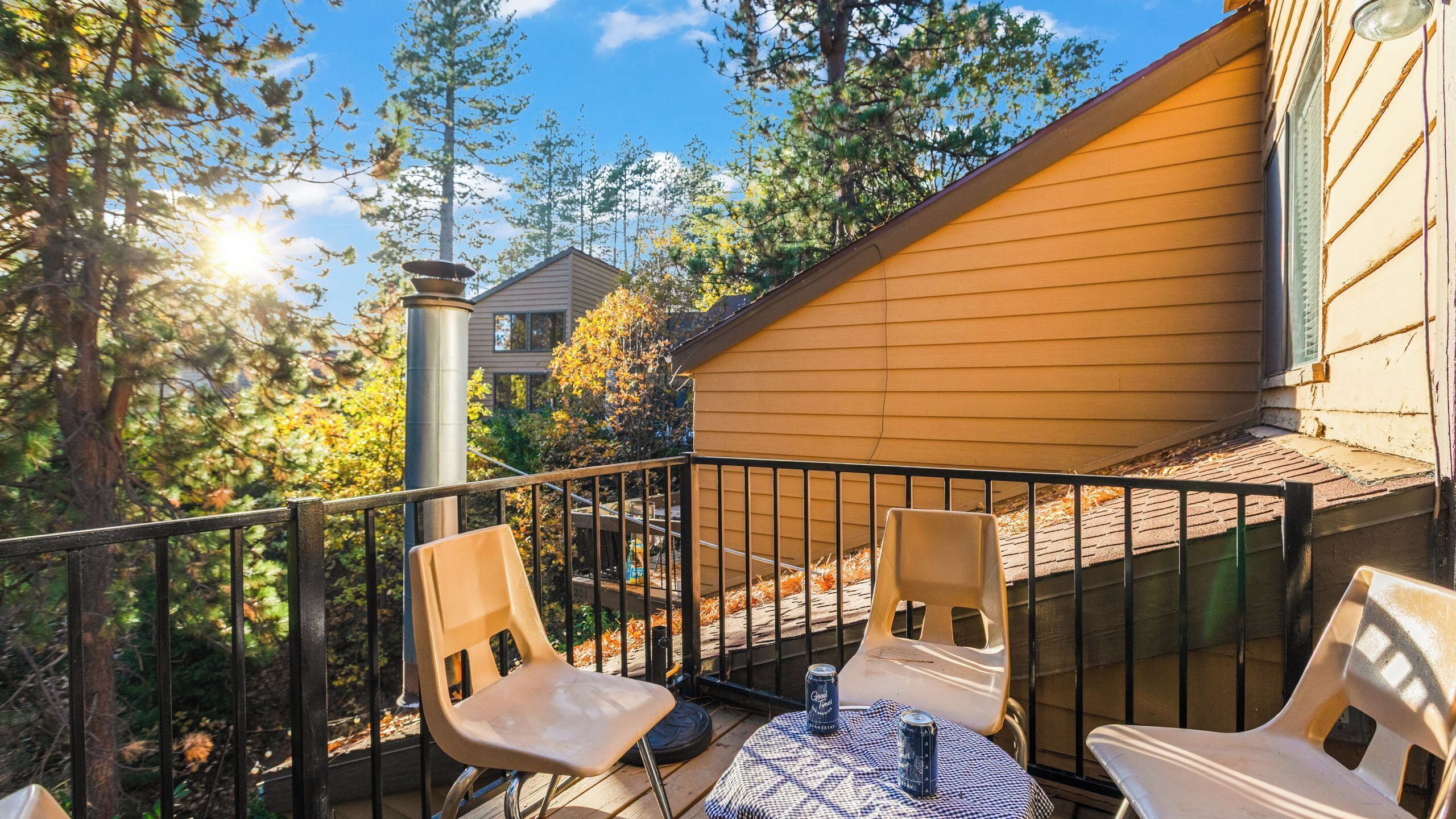 A balcony with two chairs, a table, and a can of beer.