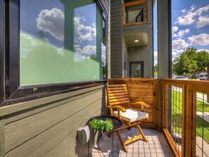 A balcony with a wooden chair, a small table with a plant, and a view of the sky. - New 1Bed Apartment A2 in OKC (Oklahoma City)