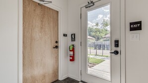 Ein Flur mit einer Holztür, einem Feuerlöscher und einem Hinweisschild für den Notausgang.