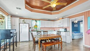 Uma cozinha espaçosa com armários brancos, uma mesa de jantar de madeira e um ventilador de teto.