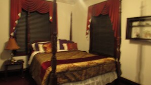 A four-poster bed with a red and gold bedspread, a wooden headboard, and a nightstand with a lamp. - Welcoming bed & breakfast with AC in charming Crofton (Crofton)