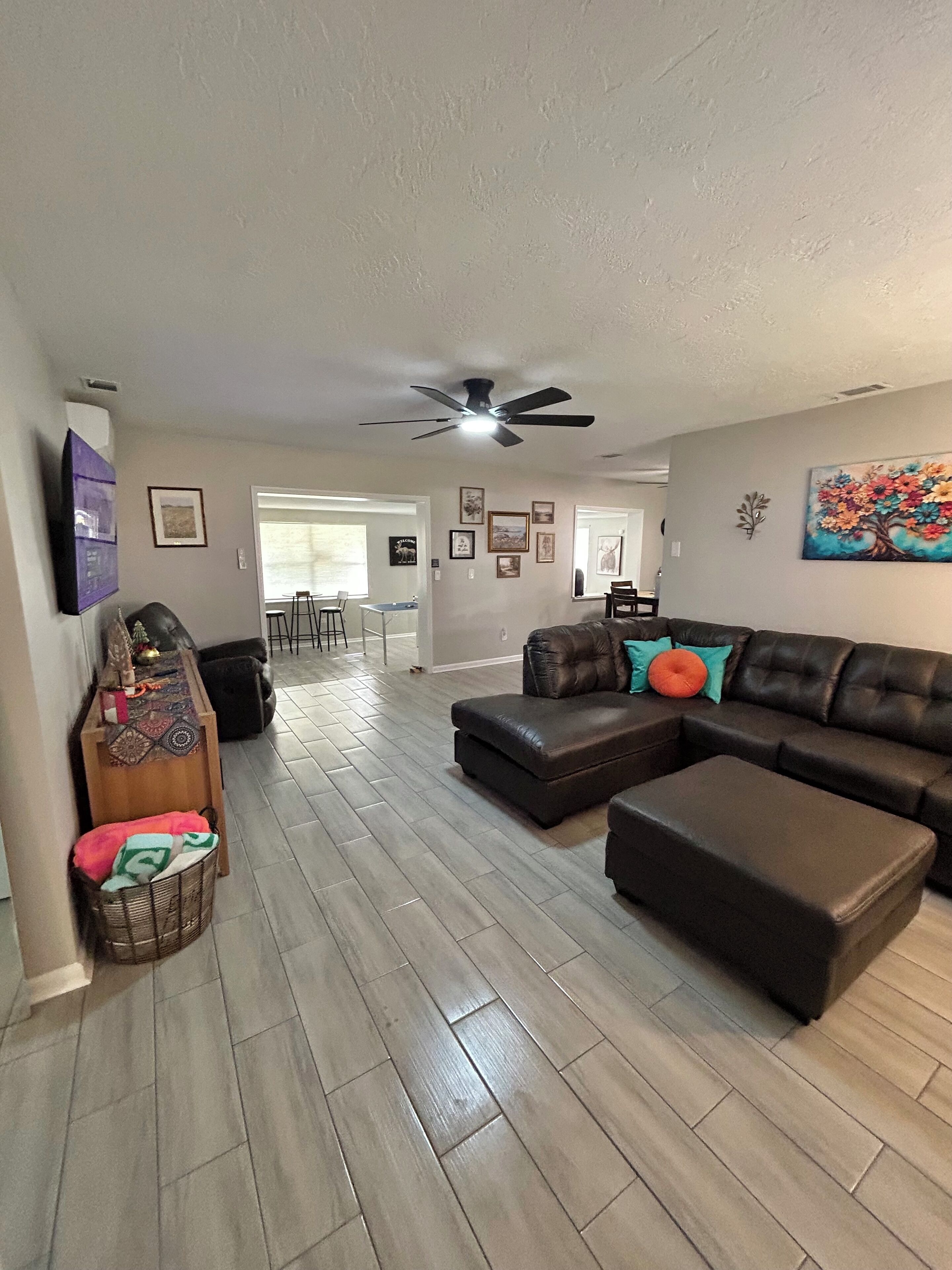 A spacious living room with a sectional sofa, a wooden coffee table, and a ceiling fan.