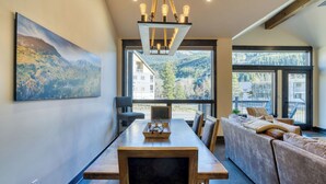 Ein modernes Interieur mit Esstisch, einer Couch und großen Fenstern, die Bergblicke bieten.