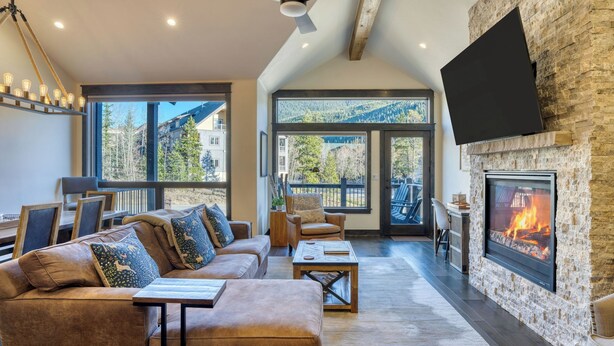 A cozy living room with a stone fireplace, large windows, and a comfortable seating area. - Fireplace, Game Room & Mountain Views Near Golf & Dining Keystone River Run by Avantstay (Keystone)
