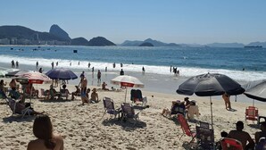 Une plage avec des gens, des parasols et des chaises.