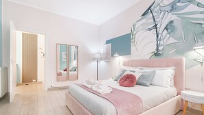 Quarto com cama, mesa de cabeceira, abajur e uma grande pintura na parede.