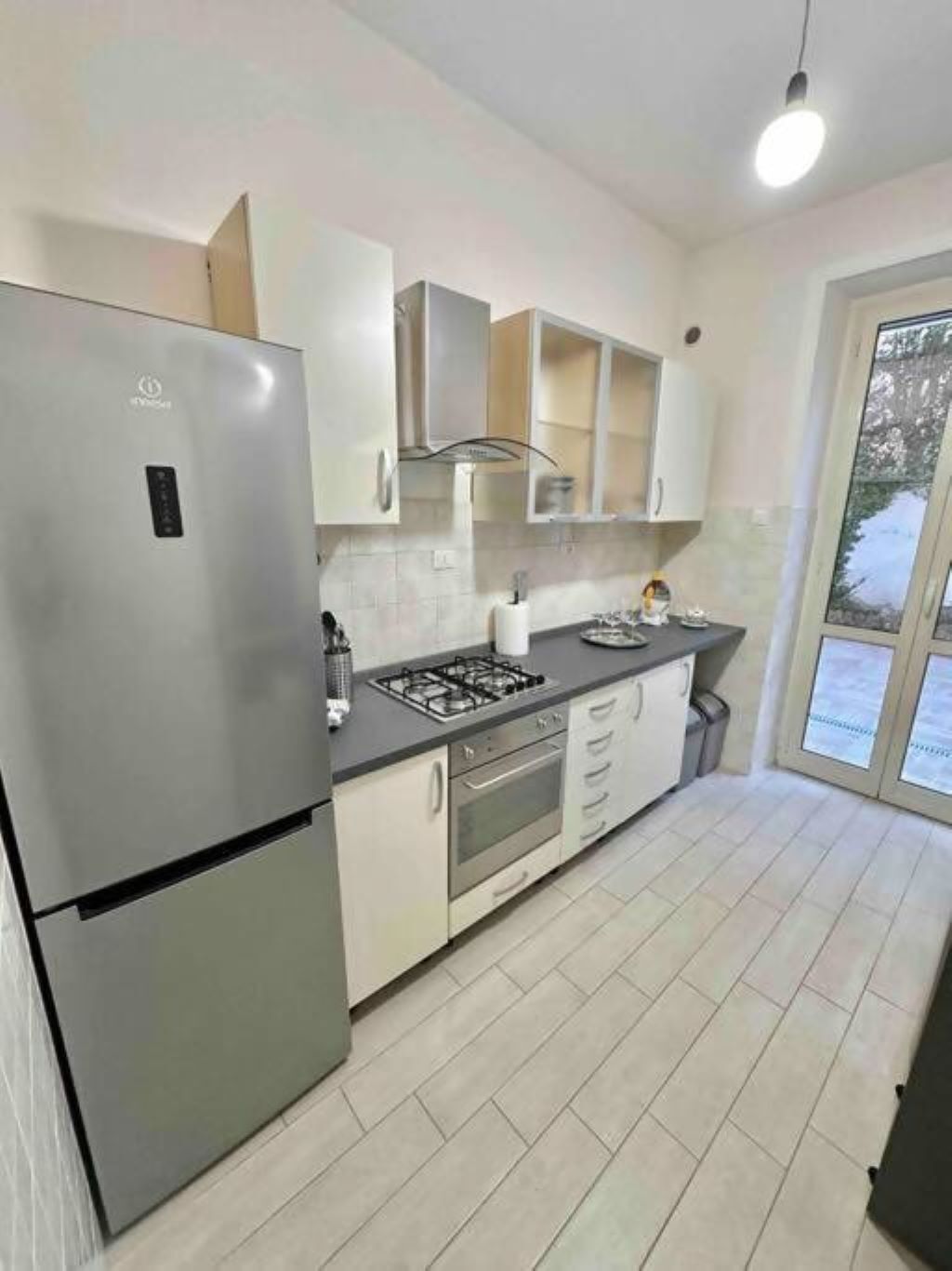 Una cocina moderna con refrigerador de acero inoxidable, estufa a gas y muebles de cocina blancos.