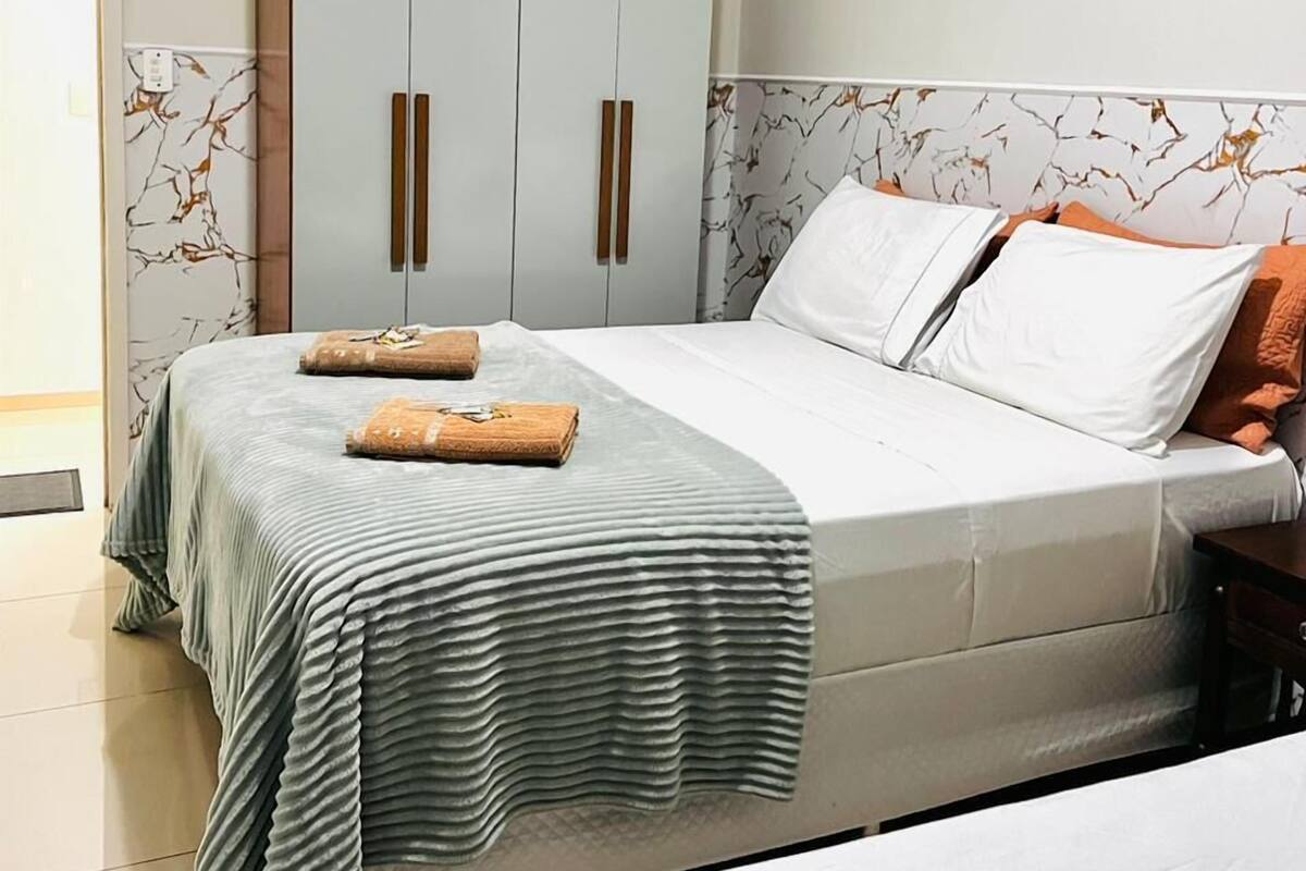 A bedroom with a bed, a wardrobe, and a bathroom.