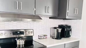 Een moderne keuken met grijze kastjes, een roestvrijstalen fornuis en een koffiezetapparaat.