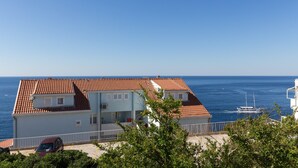A coastal building with a red-tiled roof, a balcony, and a view of the sea. - One Bedroom Apartment with Loggia and Sea View (Dubrovnik)