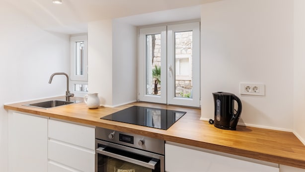 Una cucina moderna con un piano di lavoro in legno, un lavello, un fornello e una finestra vista verde.