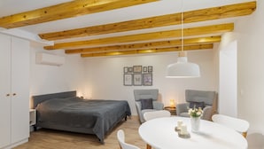 Una camera da letto con un letto, comodini, un tavolo rotondo con sedie, un lampadario e travi in legno al soffitto.
