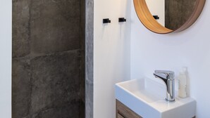 Ein modernes Badezimmer mit einem großen Spiegel, einer Dusche und einem Waschbecken mit Holzschrank.