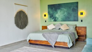 Une chambre moderne avec un lit, un tableau abstrait accroché au mur et deux appliques murales.