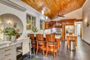 Une cuisine moderne avec des meubles en bois, un îlot central et des tabourets de bar.
