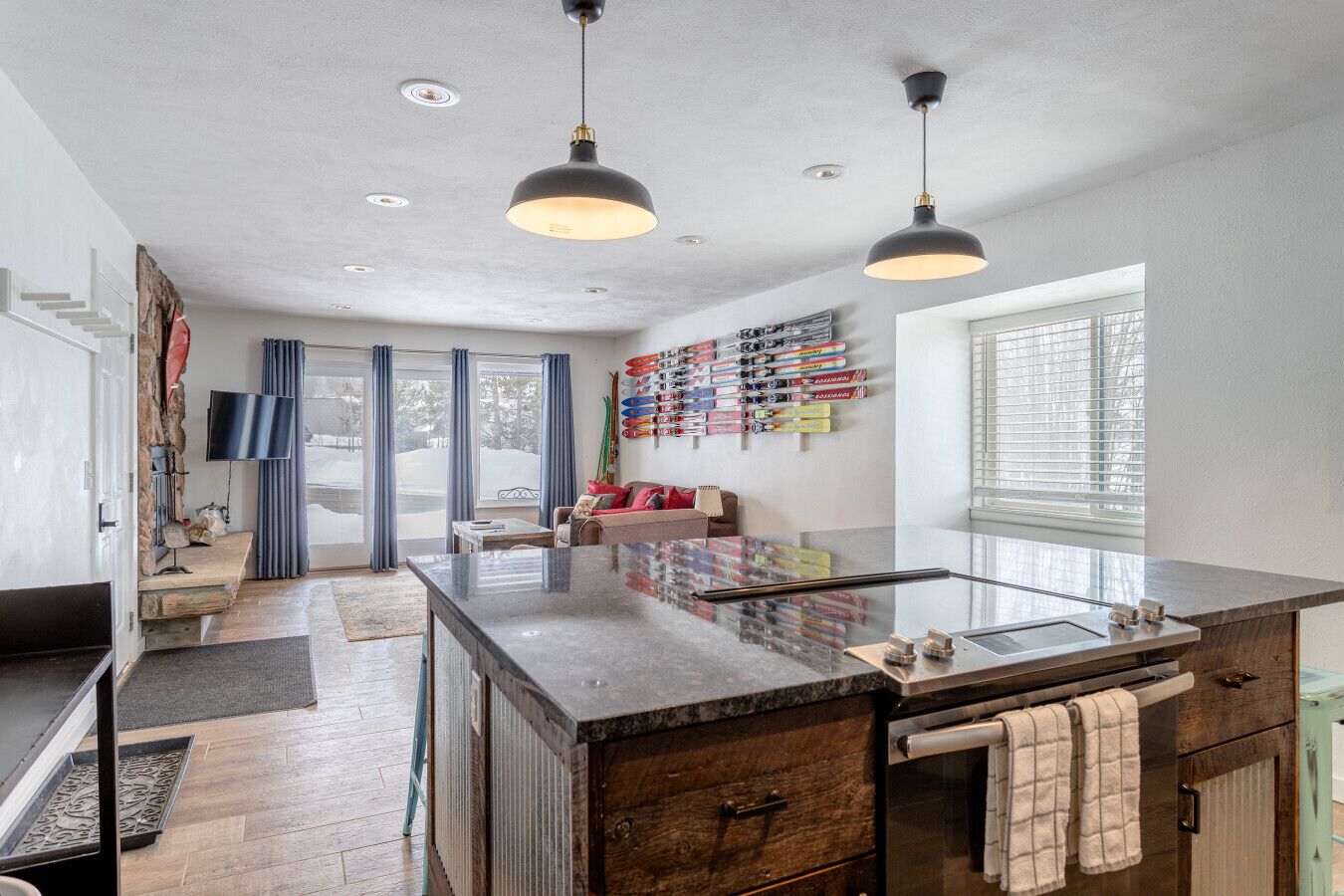 A modern kitchen with a large island, pendant lights, and a ski-themed wall.