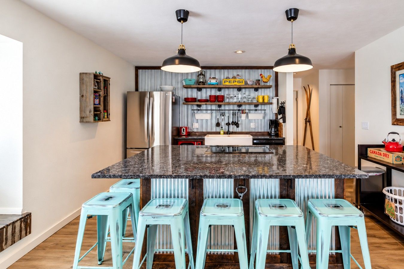 A kitchen with a central island, bar stools, and a variety of kitchen appliances and decorations.