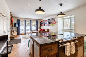 A modern kitchen with a central island, pendant lighting, and a ski rack on the wall. - Charming 2BR Fraser Escape – Fireplace, Trails & Resort Nearby! (Fraser)
