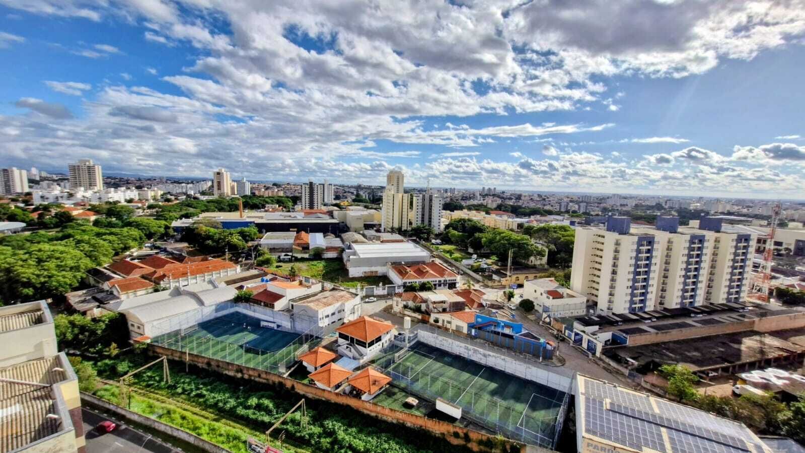 A cityscape with a mix of residential and commercial buildings, including a large sports complex with a tennis court.