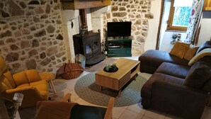 A cozy living room with a stone wall, a fireplace, a television, and comfortable seating. - Holidayhome Confolens with Heated Pool-
Tranquille Vienne Gites in the Charente (Chirac)