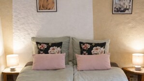 A double bed with floral pillows, a pink quilt, and two rolled towels on the bed. - Holidayhome Confolens with Heated Pool-
Tranquille Vienne Gites in the Charente (Chirac)