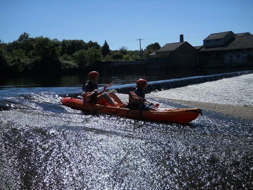 Two people in a kayak on a riverbank.