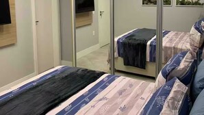 A modern bedroom with a large bed, a mirror, a TV, and artwork on the wall. - Itaim Star 2 (São Paulo)
