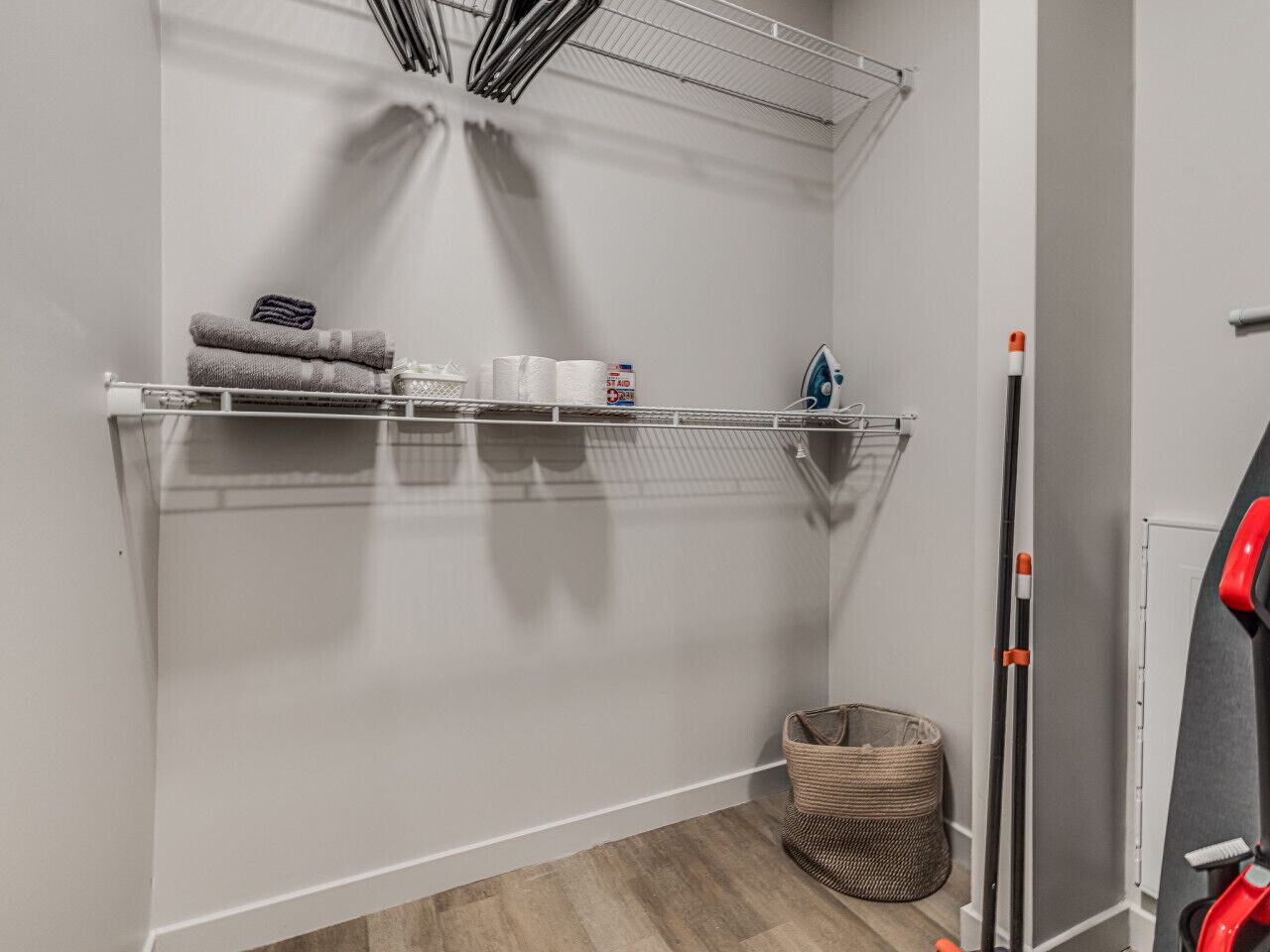 A laundry area with shelves holding towels, a basket, and a mop.