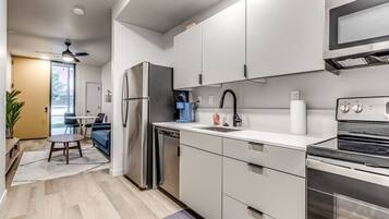 A modern kitchen with stainless steel appliances, white cabinetry, and a built-in oven.