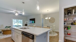 Een moderne keuken met een centraal kookeiland, een ingebouwde vaatwasser en een eethoek met een ronde tafel en stoelen.