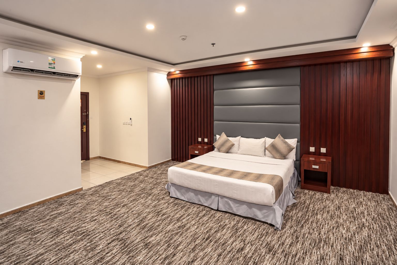 Un dormitorio moderno con una cama grande, paneles de madera y cabecero integrado.