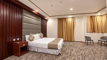 Een hotelkamer met een groot bed, een houten hoofdbord, een nachtkastje, een stoel en een vloerbedekking.