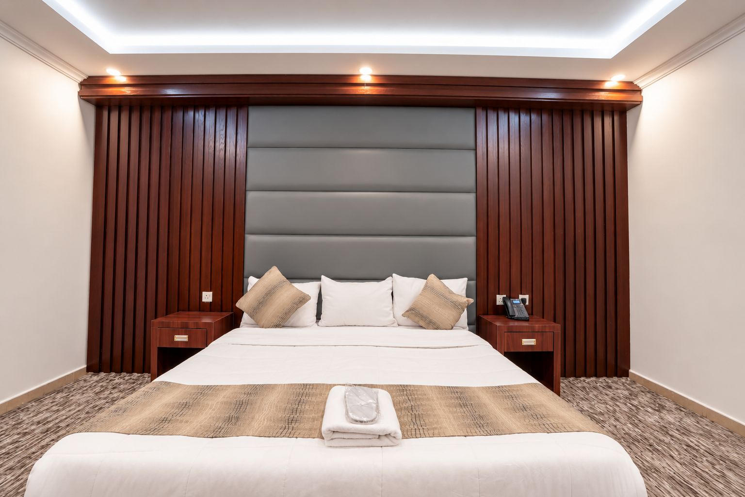 Een hotelkamer met een groot bed, twee nachtkastjes, een hoofdeinde en een plafondlamp.